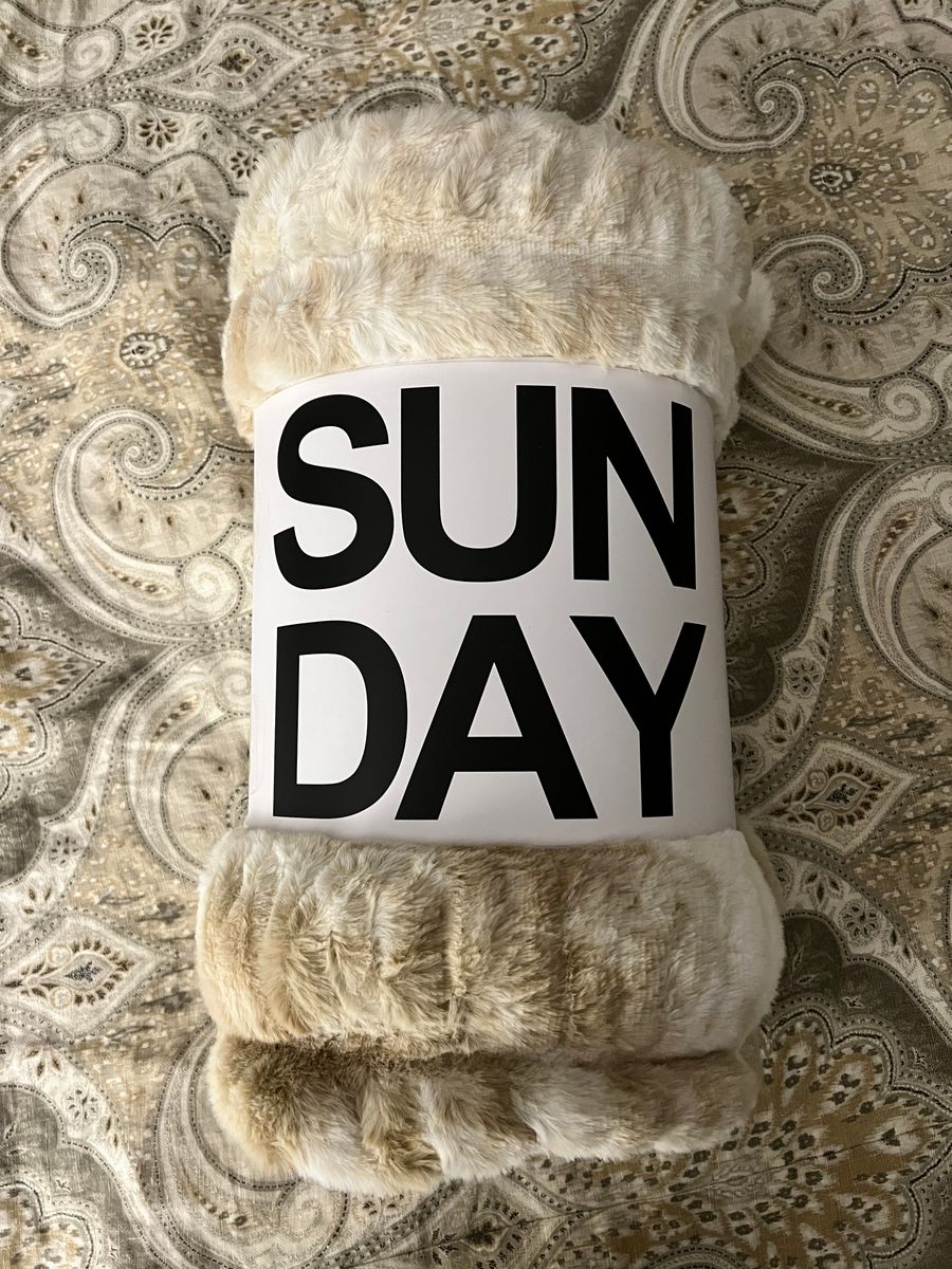 Customer photo from Katie's review: a rolled-up Ripple blanket wearing its SUN DAY band